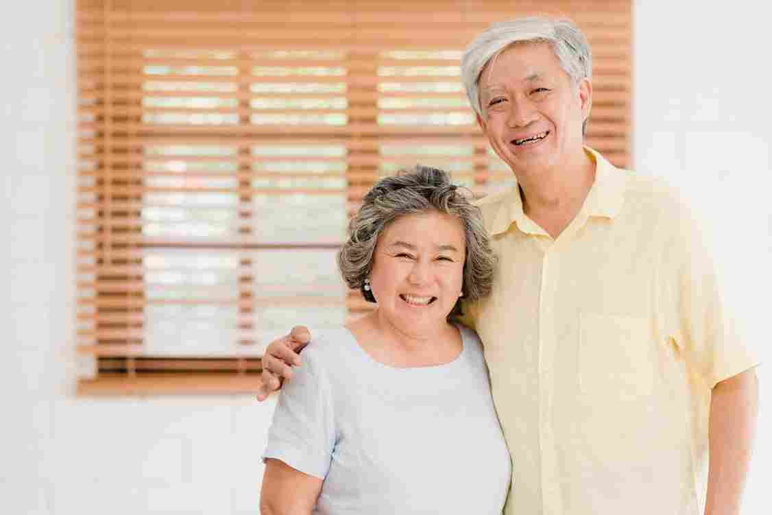 asian-elderly-couple-feeling-happy-smiling-looking-camera-while-relax-living-room-home-scaled