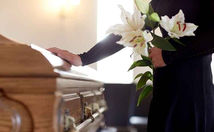 woman-with-lily-flowers-and-coffin-at-funeral